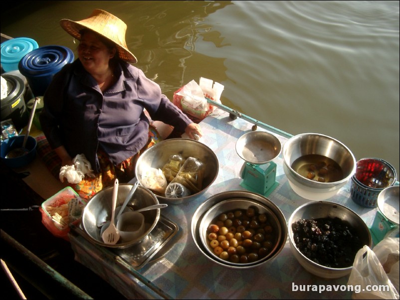 Woman selling noodles, lychee, and other things from her boat at the floating market.