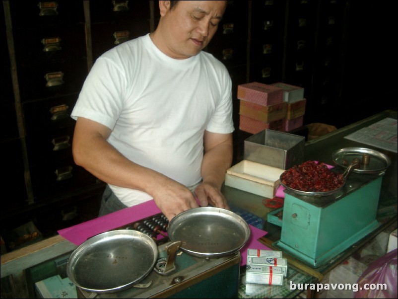 Man using an abacus at an old Chinese medicine shop.